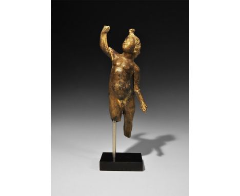 1st-2nd century AD.
A hollow-cast bronze figure of Cupid standing nude with right arm raised supporting a cornucopia, left ar