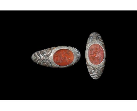 3rd century AD. A D-section silver hop with angled shoulders, incised scroll motifs, plaque with carnelian insert, intaglio m