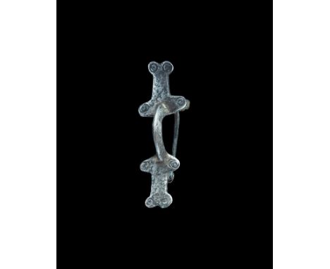 6th-8th century AD. A silver bow brooch formed as two T-shaped plaques joined by a C-shaped bow, each plaque with lateral lob