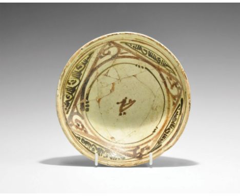 9th-10th century AD. A rounded green-glazed ceramic bowl with pedestal base, band of black painted foliage ornament to the ou