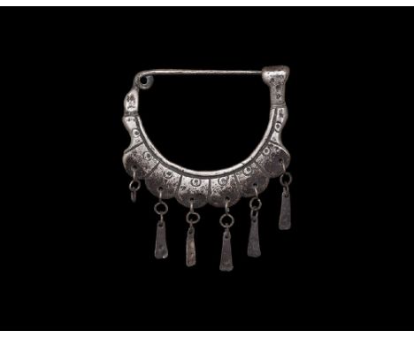 8th-7th century BC. A silver fibula with D-shaped plaque, integral coiled spring and pin, catchplate finial; the plaque with 