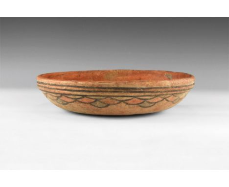 4th-3rd millennium BC. A ceramic dish with thick rim and body painted with scale pattern in brown, red and blue; interior of 