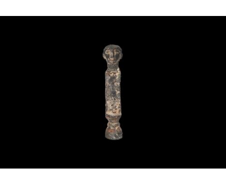 2nd millennium BC. A bronze mount or finial with D-section body, balustered lower finial with collar, upper finial a human he