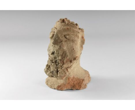 1st-3rd century AD. A ceramic head of a male with large eyes, smiling mouth and bushy beard; short neck with flat base. 423 g