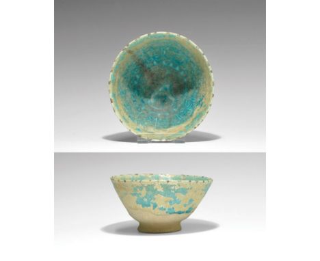 12th-14th century AD. A glazed ceramic bowl with flared foot; the surface covered with a deep turquoise glaze with iridescenc