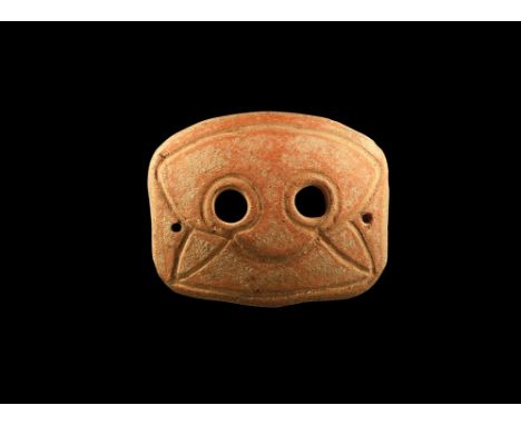 4th-3rd century BC. A rectangular slightly curved ceramic mask with two eye-holes and incised stylised facial details; pierce