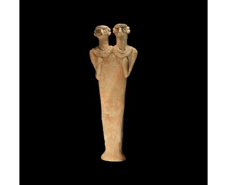 12th-8th century BC. A large ceramic figurine with columnar body and flared base, applied discs to the breasts, right arm fle