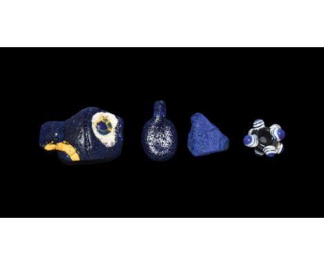 1st century BC and later. A mixed group comprising: a black glass spherical bead with eight radiating eyes; a blue glass drop