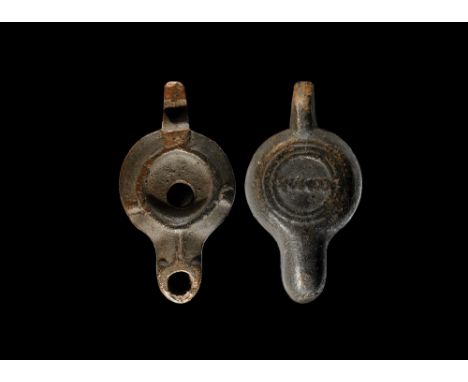 1st-3rd century AD. A ceramic oil lamp with ridged oil chamber and lugs to three of the sides, projecting handle and nozzle; 