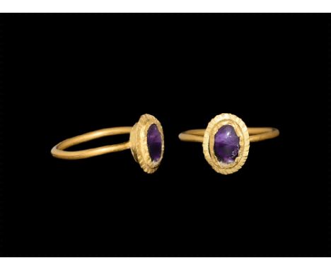 1st-3rd century AD.
A gold ring with thin shank; bezel with rope pattern surrounding an amethyst. 2.82 grams, 19.76mm overall