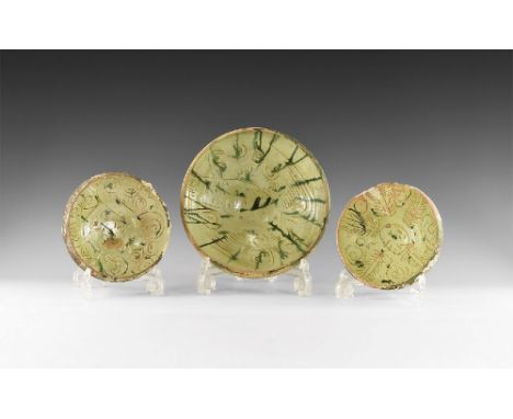 8th-10th century AD. A group of three ceramic footed bowls, each with green glaze to the inner face and sgraffito design comp