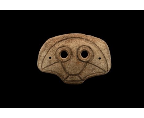 4th-3rd century BC. A D-shaped slightly curved ceramic mask with two eye-holes and incised stylised facial details; pierced a