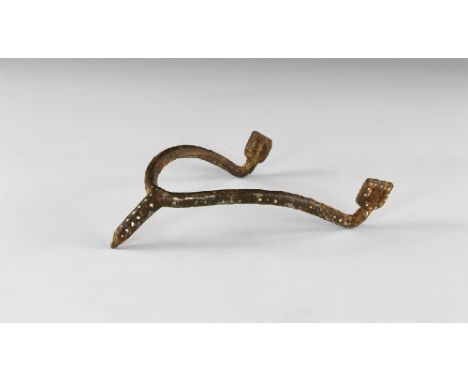 11th century AD. An iron prick spur comprising the round-section U-shaped shank with two square strap plates and a tubular pr
