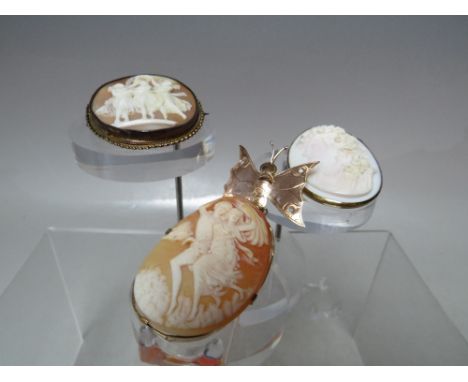 A COLLECTION OF THREE VINTAGE CARVED CAMEO BROOCHES. comprising a yellow metal framed cameo depicting a young couple in perio