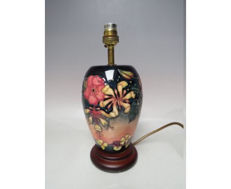 A MOORCROFT 'HONEYSUCKLE' PATTERN TABLE LAMP, with typical tube lined decoration, raised on a circular wooden plinth, overall