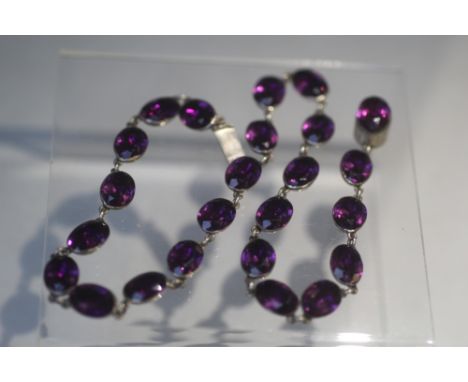 A VINTAGE HAND CRAFTED WHITE METAL AND AMETHYST TYPE COLLARETTE, set with 24 oval faceted stones, overall length 41 cm