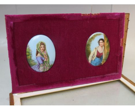 A FRAMED AND GLAZED PAIR OF HAND PAINTED CONTINENTAL STYLE CERAMIC PLAQUES, of oval form, mounted on fabric, framed and glaze