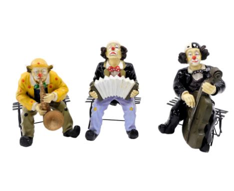 Three resin clown figures, each seated, comprising one playing trumpet, another cello, 25cm high. (3)