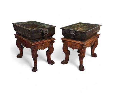A near pair of massive Chinese patinated bronze planters on oak stands, with elephant and dragon handles, relief moulded frie