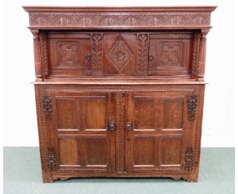 A late 17th century joined oak court / press cupboard, the lunette carved frieze over a lozenge carved fixed central panel, f