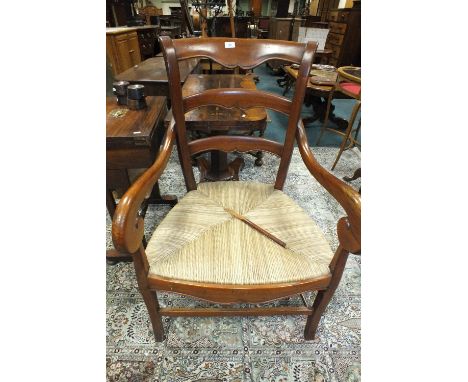 A French cherry wood ladder back open armchair of large proportions with rush seat and scroll arms