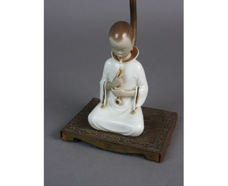 A figural table lamp, late 19th/early 20th century modelled as a kneeling porcelain figure of a girl smoking a pipe and kneel