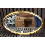 An oval bevel edged mirror in fancy gilt frame