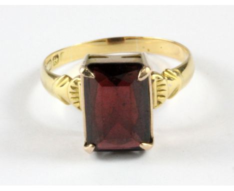 An 18ct yellow gold ring set with an emerald cut garnet, (Q.5).