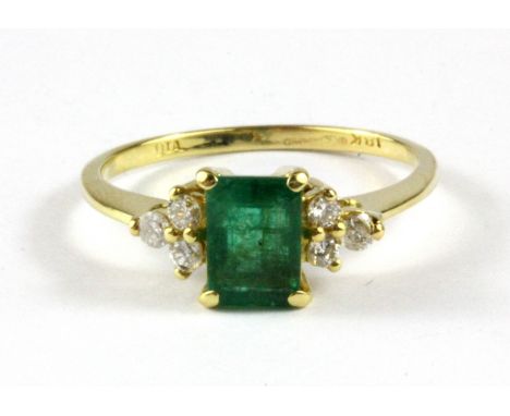 An 18ct yellow gold ring set with an emerald cut emerald and diamond set shoulders, (N.5).