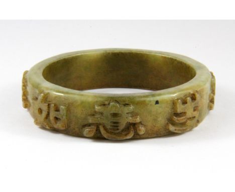A mid 20th Century Chinese carved nephrite jade bangle decorated with characters in relief, W. 1.8cm. Inner Dia. 6.4cm.