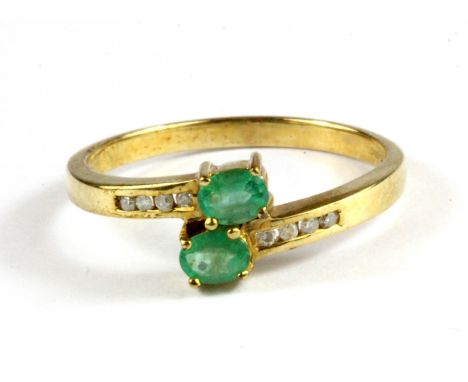 A 9ct yellow gold emerald and diamond set crossover ring, (P.5).