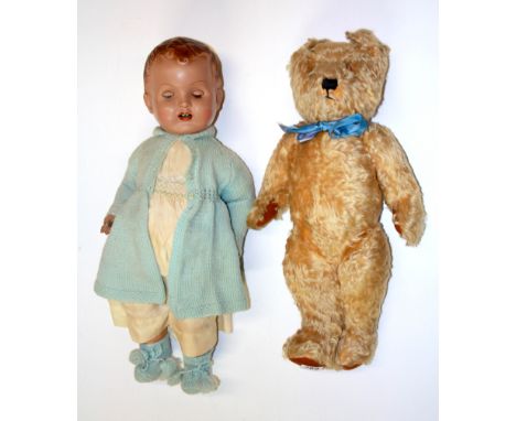 An articulated plush British teddy bear and a composition child doll, doll height 60cm.