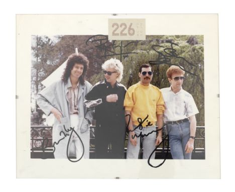 Queen: An autographed colour photograph,circa 1985,the group portrait signed in black marker by Freddie Mercury, Brian May, J