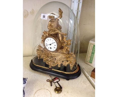 A late 19th century French gilt metal cased mantle clock with male figure surmount and enamel dial under glass dome on wooden