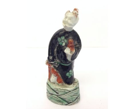 A small Chinese porcelain figure modelled as a gent in black cloak holding a pot in his left hand (11cm).