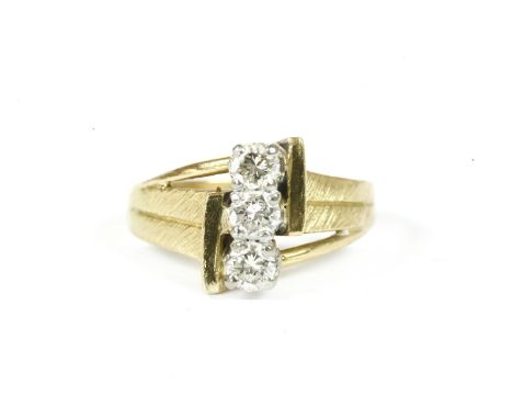 An 18ct gold three stone portrait brilliant cut diamond ring, with open textured shoulder and a plain polished shank, size H3