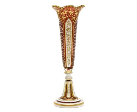 A late 19th century Bohemian ruby glass and enamelled spill vase, with gilded decoration, 25cm high