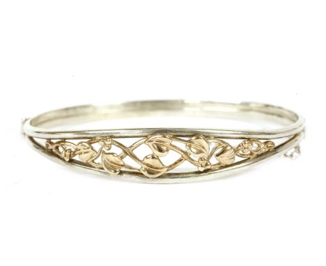 A sterling silver and Welsh gold hinge bangle, by Clogau, with openwork scrolling leaf design to top section12.38g