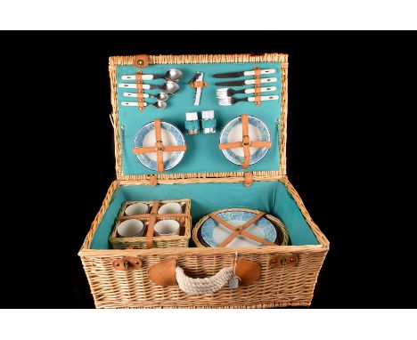 A Wicker Picnic hamper, complete with 4 place settings including plates, bowls, mugs, and cutlery. 