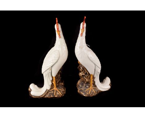A Pair of ceramic Cockerels, of stylised slender form in white with painted heads and bases (repair to one comb) AF. 