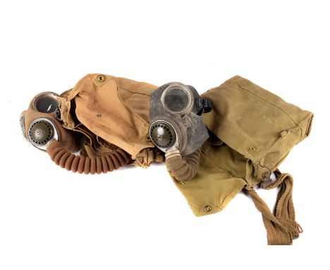 Two WWII gas masks, both marked with broad arrow, one rubber, the other fabric, both having corrigated tube and cannister, in