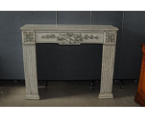 A Georgian period fire place surround, the white painted wooden arch in the neo-classical taste with raised designs 
