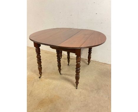 A French mahogany pull-out dining table on turned legs and castors, height 70cm, width 118 cm, depth 96cm.