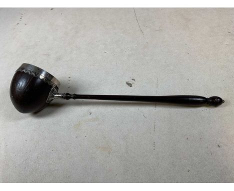 A George III coconut cup white metal mounted and turned wooden handled ladle, unmarked, length 33cm.