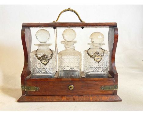 An oak three bottle tantalus with two alcohol labels, decanters and tantalus a/f.