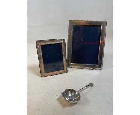 Two hallmarked silver photo frames and a silver tea strainer, height of tallest frame 23cm