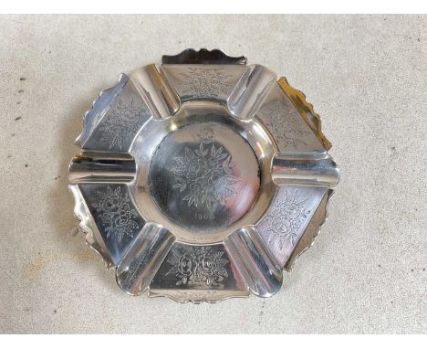 An Indian white metal hexagonal ashtray with engraved floral detail and with initials and date 1906 to the central panel, the