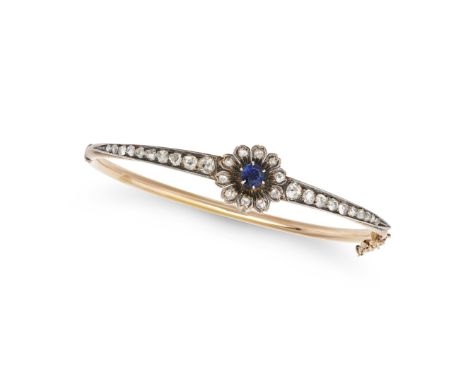 AN ANTIQUE SAPPHIRE AND DIAMOND BANGLE in yellow gold and silver, the hinged bangle set with a round cut sapphire in a cluste