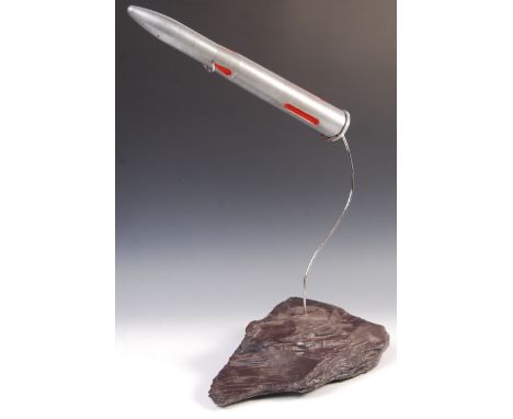 A retro vintage sputnik atomic trench art style art sculpture depicting a rocket on stand shooting around some form of space 
