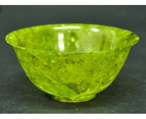A CHINESE JADE LIKE BOWL, of green tone with darker and lighter inclusions, 3.9in diameter.